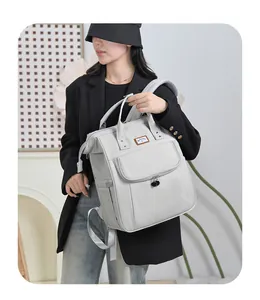 Modern grey maternity backpack with top handles and adjustable straps worn by a model