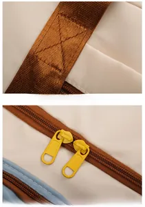Close-up of reinforced brown straps and dual-way gold zippers on the travel bag