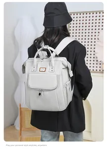 Detail view of a light grey multi-functional diaper backpack with durable fabric and logo