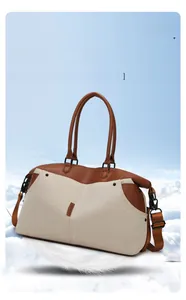 Detail of canvas travel bag featuring leather handles and adjustable shoulder strap