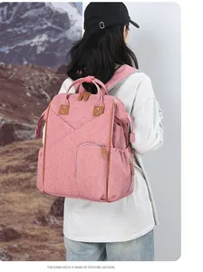 Dettaglio della borsa fasciatoio rosa con manici in pelle martellata su sfondo innevato