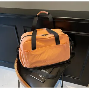 Vue détaillée du sac de sport rose orange imperméable avec poignées noires et bandoulière