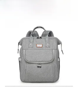 Front view of grey diaper backpack featuring top handles and brown leather logo patch