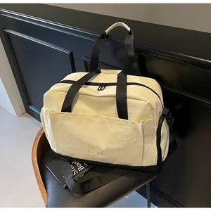 Détail du sac de sport crème avec sangles noires et grande poche avant sur siège noir