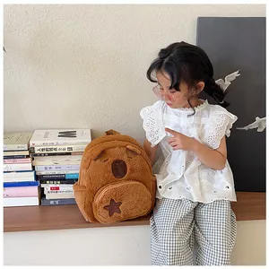 Close-up of a cute plush Capybara backpack with a star detail on a soft brown texture