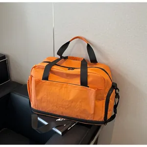 Vue détaillée du sac de sport orange avec tissu en nylon imperméable et compartiment chaussures