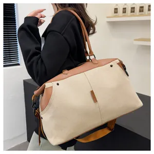 Detailed side view of large canvas travel tote bag with brown leather trim on model