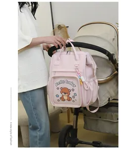 Zaino fasciatoio rosa con stampa orsetto appeso al manico del passeggino in uso