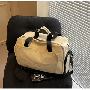 Détail du sac de sport blanc cassé avec sangles noires et poche latérale à fermeture éclair