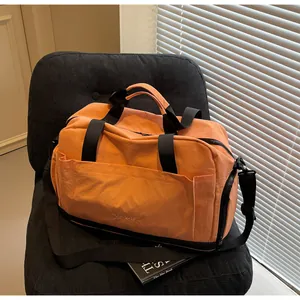 Détail du sac de sport orange avec compartiment à chaussures et bandoulière amovible