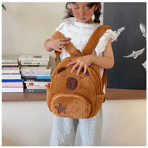 Detail shot of a brown plush capybara backpack with embroidery on a young girl model