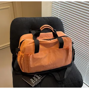 Détail du sac de fitness orange imperméable avec sangles noires sous la lumière