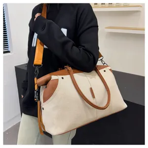 Detail of canvas travel bag with brown leather trim and bright orange nylon shoulder strap
