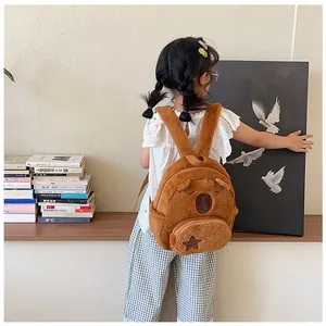 Close-up of plush brown bear backpack for kids with 3D ears and star patch detail
