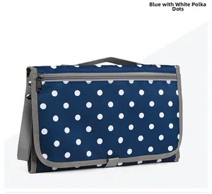 Folded blue polka dot diaper changing pad with grey handle and waterproof fabric