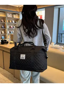Detail of black quilted travel bag with woven label and adjustable nylon shoulder strap