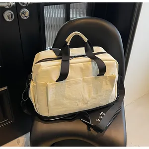 Détail du sac de fitness blanc cassé avec poches multiples et logo GULVCHE sur chaise