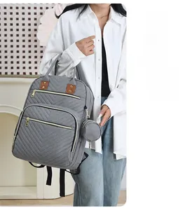 Detail view of grey quilted diaper backpack with side round coin purse and brown leather handle