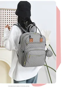 Detail view of grey diaper backpack with quilted fabric and leather handles on a model