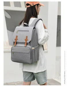 Close-up of grey diaper backpack with brown leather straps and multi-pocket design