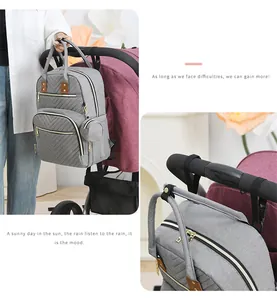 Detail of grey mommy backpack hanging on stroller with V-quilted texture and small pouch