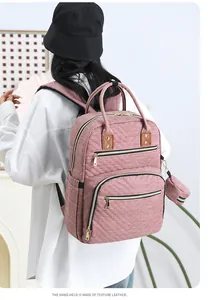 Detail view of mauve quilted diaper backpack with leather handles and gold zippers