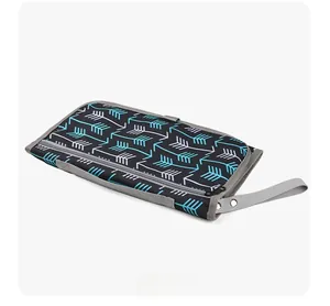 Folded portable baby diaper changing pad with blue arrow pattern and gray carrying strap