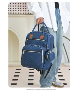 Detailed view of blue V-quilted diaper backpack with gold zippers and mini pouch