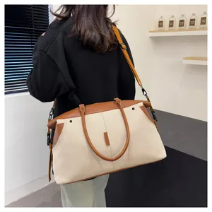 Detailed view of cream canvas travel bag with brown leather straps shown on a model