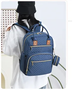 Detail of navy blue quilted diaper backpack with gold zippers and round charm hanging