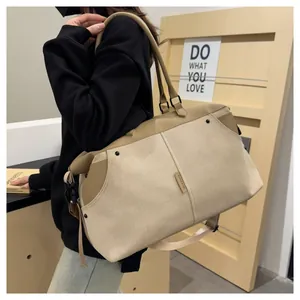 Detail of beige canvas travel bag featuring premium leather handles and metal rivets