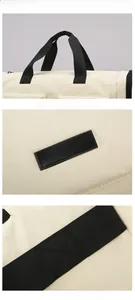 Detailed close-up of beige travel bag fabric with logo plate and reinforced stitching