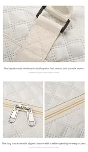 Detail of quilted travel bag showing reinforced shoulder strap stitching and dual metal zippers