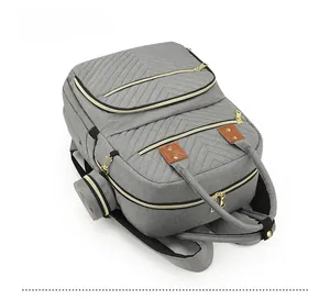 Top view of grey quilted diaper backpack with gold hardware and accessory pouch