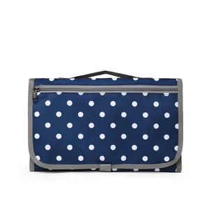 Portable waterproof diaper changing pad in dark blue polka dot print with handle