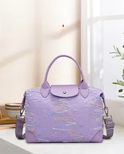 Close-up of large purple travel bag with textured diamond pattern and colorful embroidery