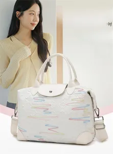Detail of white travel bag with embroidered wave patterns and textured logo surface