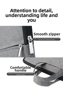 Detail view of smooth metal double zippers and durable webbing handle on gray laptop bag