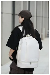 Outdoor shot showing the large capacity cream travel backpack with dual zippers on a model