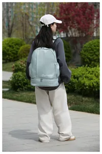 Outdoor shot of mint green travel backpack featuring a dry wet separation bottom compartment