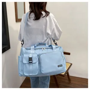 Detalle de bolsa de deporte azul claro con múltiples bolsillos y correa ajustable