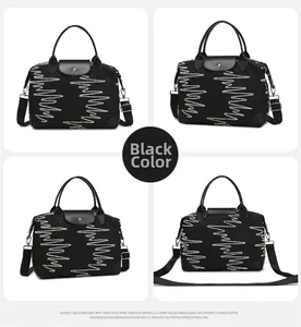 Detail view of large black travel bag with heart pattern embroidery and leather handles