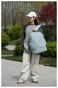 Detail view of a light blue travel backpack featuring waterproof fabric and bottom compartment