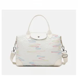 Close-up of a white quilted tote bag with colorful embroidery and a detachable strap