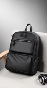 Close-up of black waterproof nylon backpack with front zippers on a grey sofa