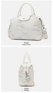 Detailed side view of white quilted travel bag with colorful embroidery and woven strap
