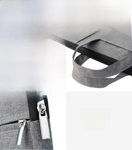 Detail view of reinforced fabric handles and metal zipper on grey oxford business bag