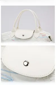 Detailed macro view of white textured PU leather bag with embroidery and silver snap button