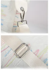 Detail of silver metal lobster clasp and D-ring on white embroidered travel bag