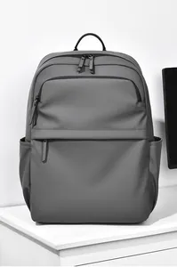 Matte grey 15.6 inch laptop backpack with dual zippers shown in a minimalist room setting